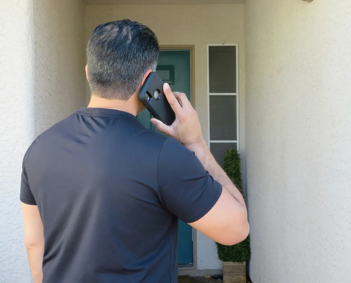 A homeowner calling a service company from his front door