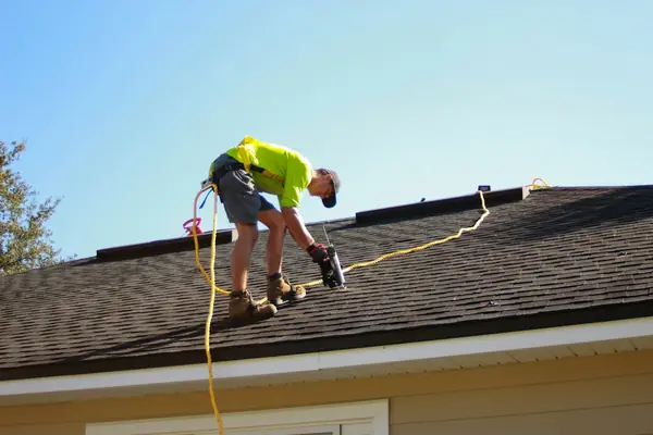 A roofer working on a shingled roof